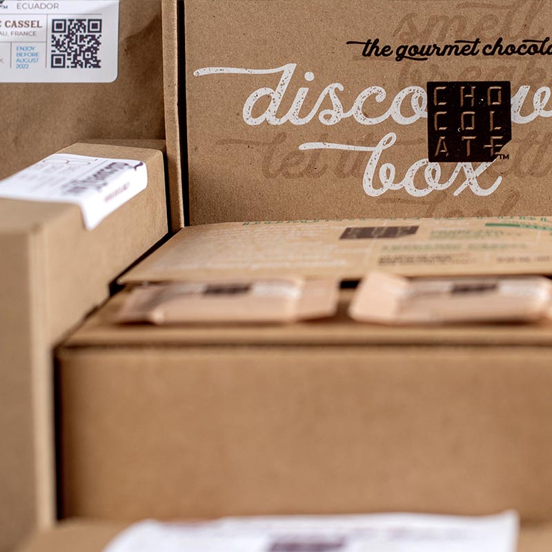 A variety of boxes and packages of Chocolat-e including a discovery box, chocolate bars, and individually wrapped chocolate bites.