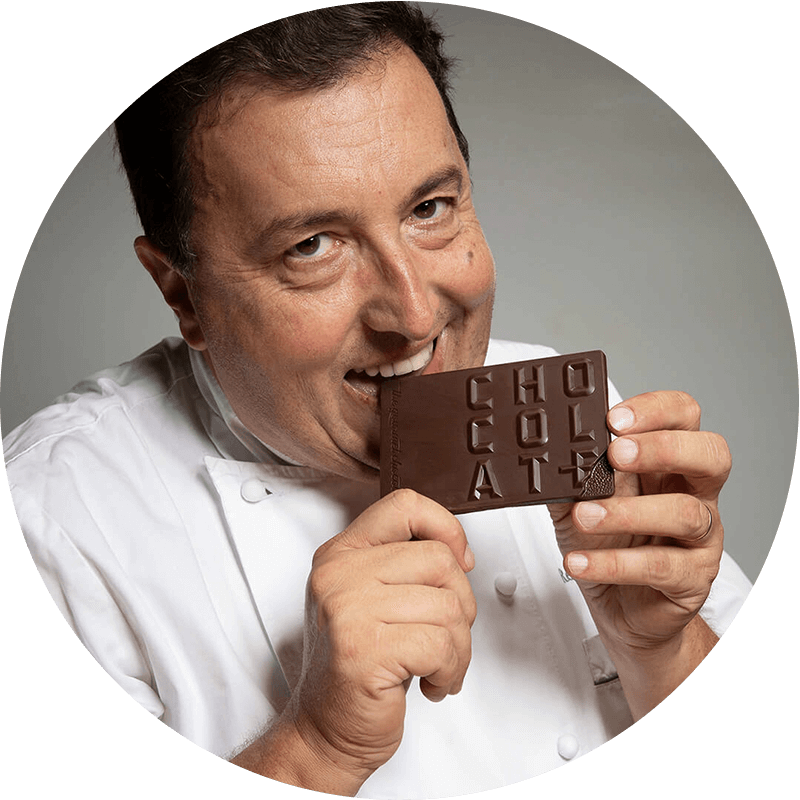 Frederic Cassel smiles at the camera while taking a bite of a Chocolat-e gourmet chocolate bar.