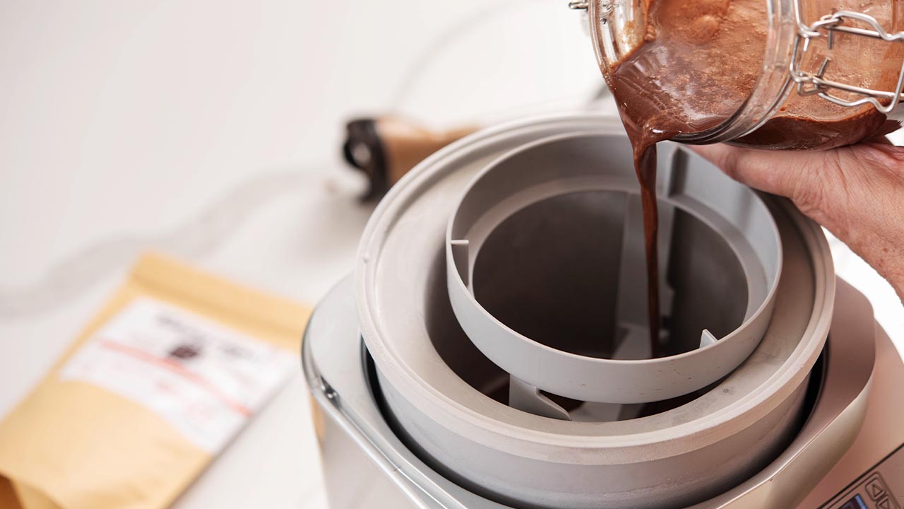 Melted chocolate is being poured into an ice cream maker.