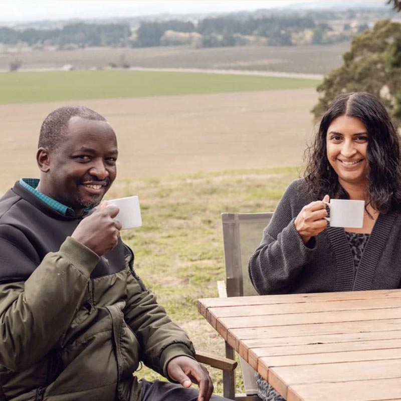 Two people, including Francis Kungu, sit at a table drinking coffee.