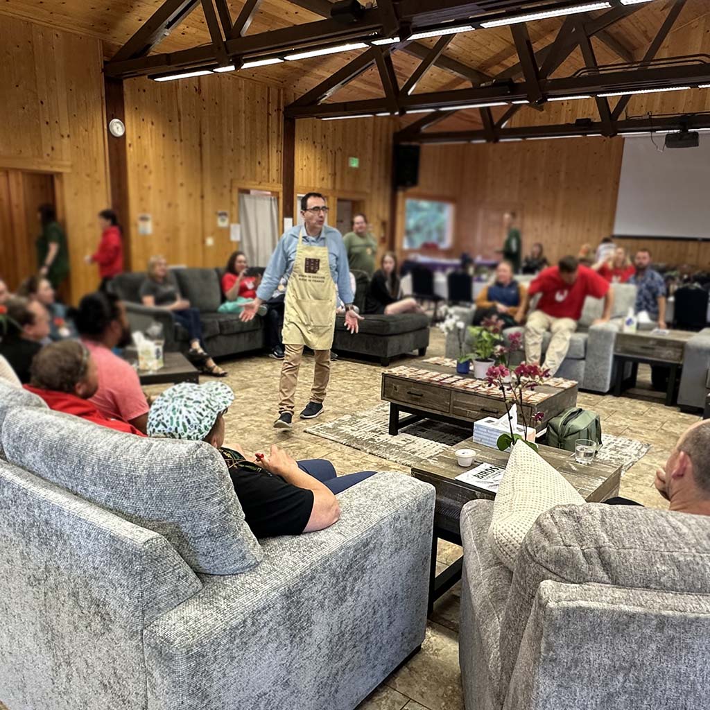 Jeanyves is wearing a Chocolat-e apron and is addressing a room full of people.