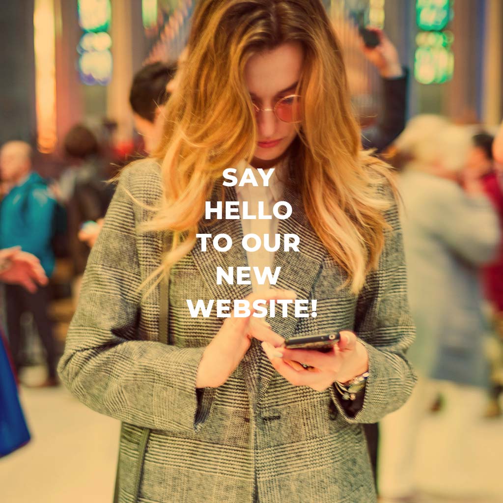 Say hello to our new website. A person is on their cell phone with a crowd of people behind them.
